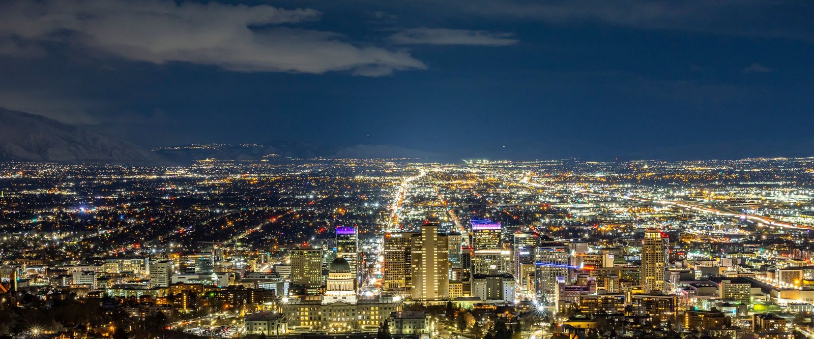 Downtown Salt Lake City at night seen from the foothills, the
        street grid picked out in light all the way across the valley to the
        dark line of the Oquirrh Mountains.